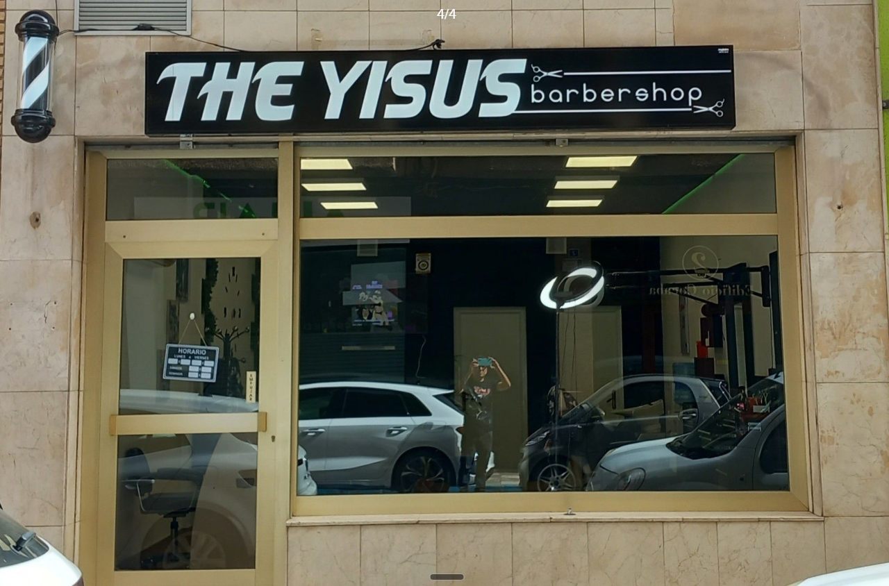 Escaparate de The Yisusbarbershop con el vinilo del logo y el poste de barbero