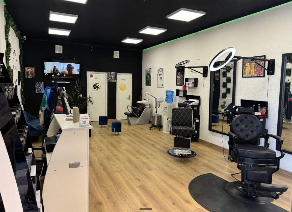 Interior de The Yisusbarbershop: techo negro con luz LED verde, sillones de barbero clásicos y suelo de madera